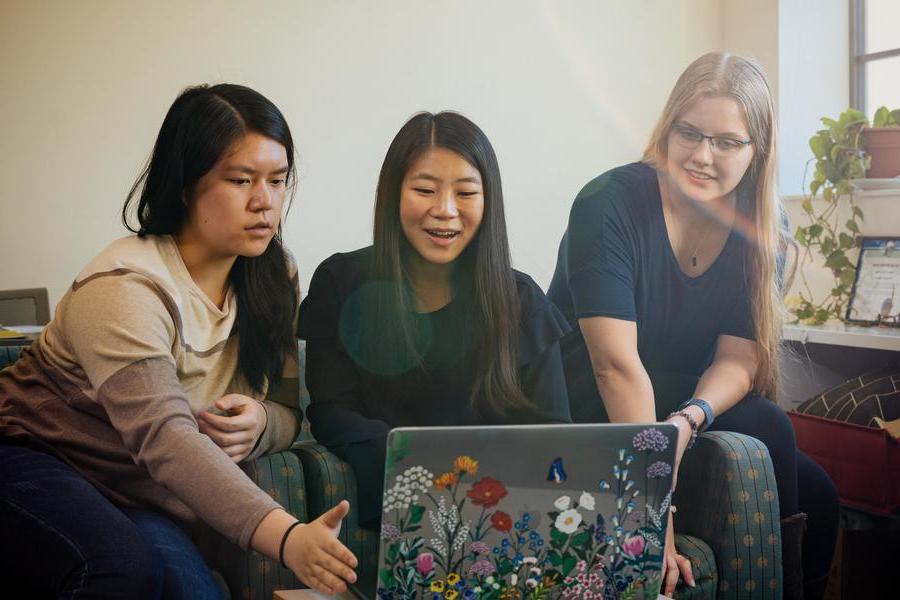 Three students around laptop